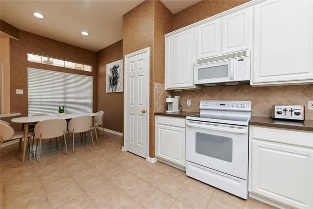 a kitchen with white cabinets and white appliances