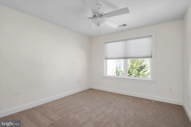 an empty room with windows and a ceiling fan