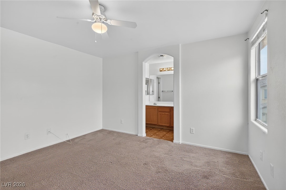 8038 Kings Ransom Street Las Vegas, NV 89139 - Photo 17 of 38 Unfurnished bedroom featuring a ceiling fan, ensuite bath, carpet flooring, and arched walkways