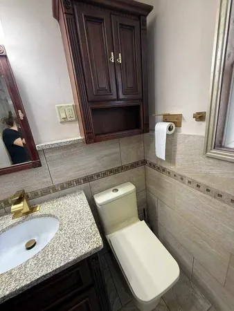 a bathroom with a granite countertop toilet sink and mirror
