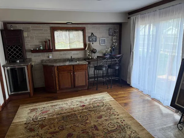 a room with kitchen island granite countertop wooden cabinets a sink a window and appliances