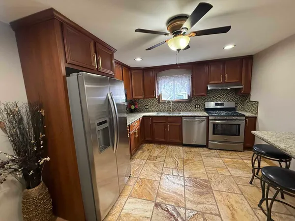 a kitchen with granite countertop a refrigerator a sink a stove and cabinets