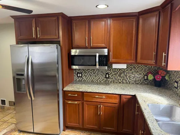 a kitchen with stainless steel appliances granite countertop wooden cabinets a refrigerator and a sink