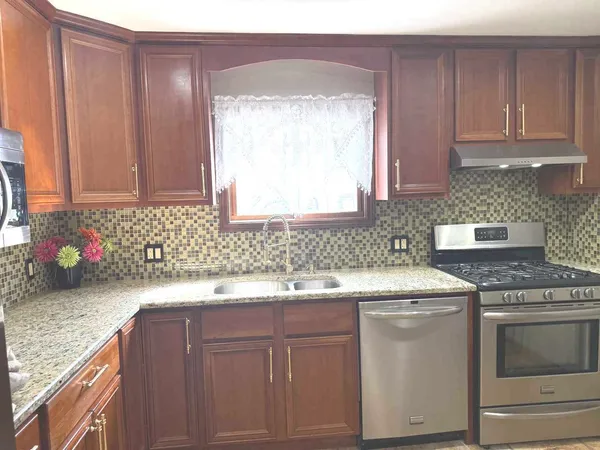 a kitchen with granite countertop a sink stainless steel appliances and cabinets