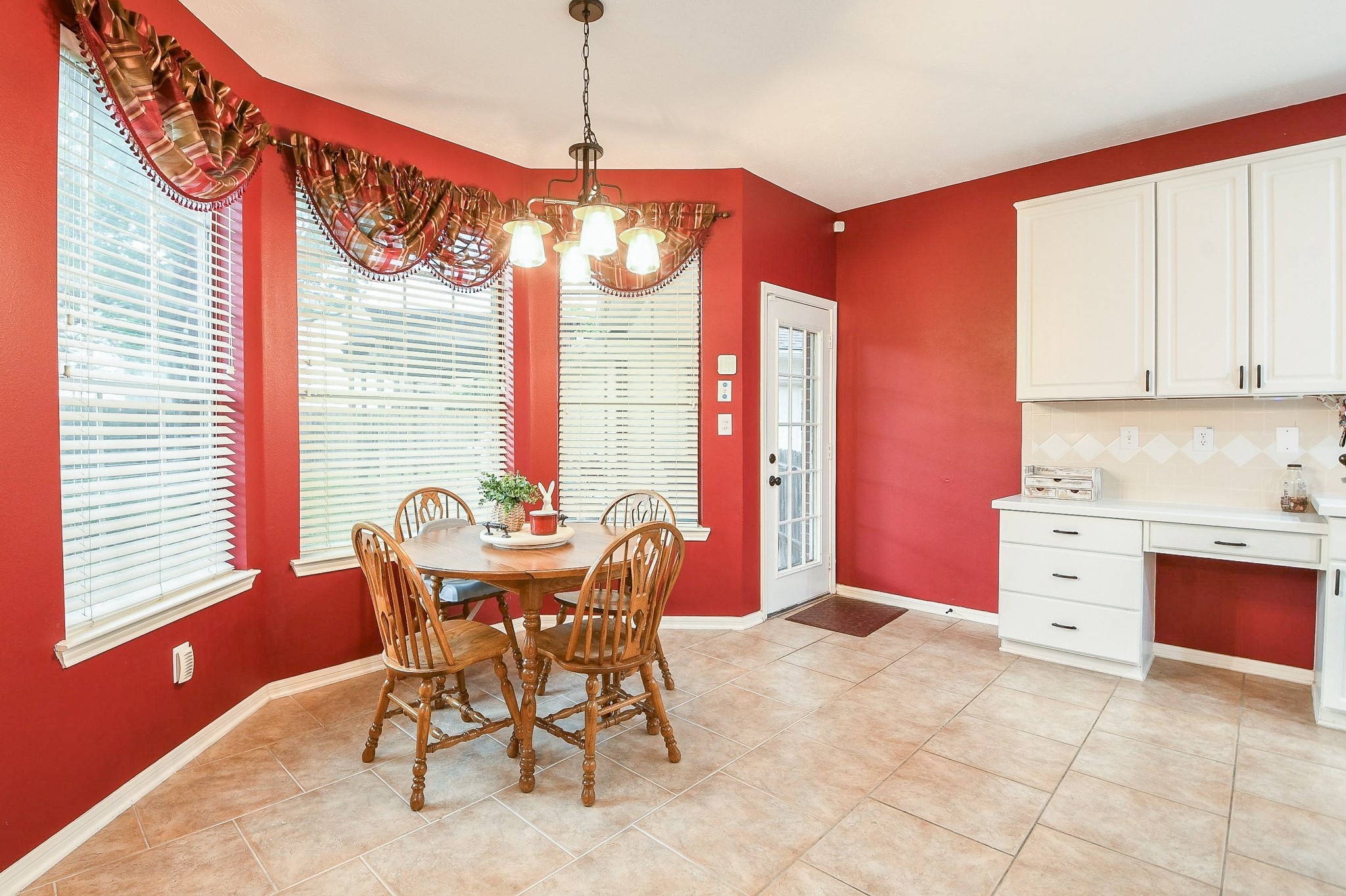 20423 Forest Drive Spring, TX 77388 - Photo 15 of 49 The inviting breakfast nook features large bay windows, and a cozy dining area with access to the backyard. Adjacent is a practical workspace with white cabinetry, offering functionality and style.