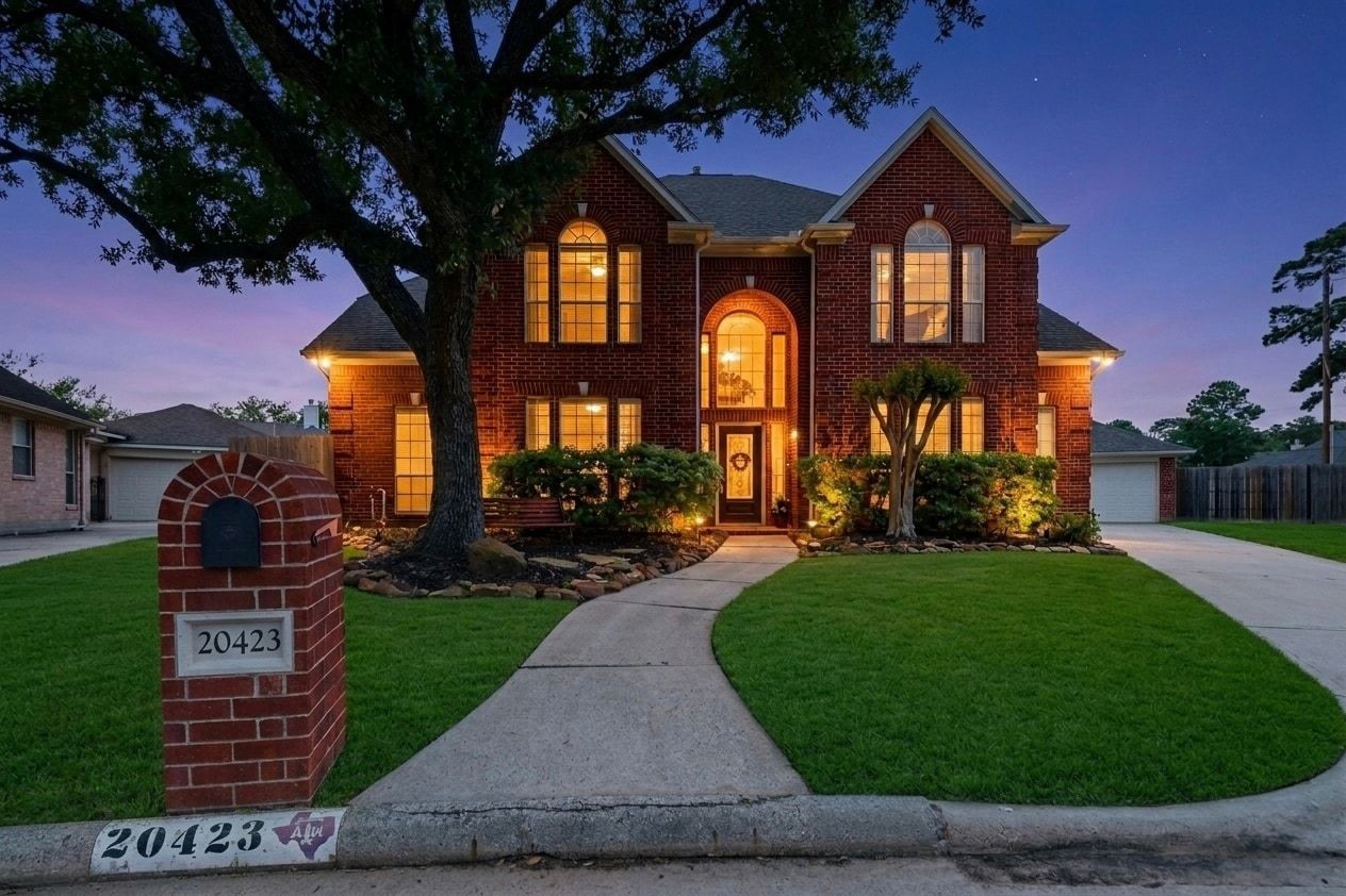 20423 Forest Drive Spring, TX 77388 - Photo 2 of 49 This inviting two-story brick home features elegant arched windows and a warmly lit entrance. It's surrounded by well-maintained landscaping and set in a serene neighborhood, creating a welcoming curb appeal.