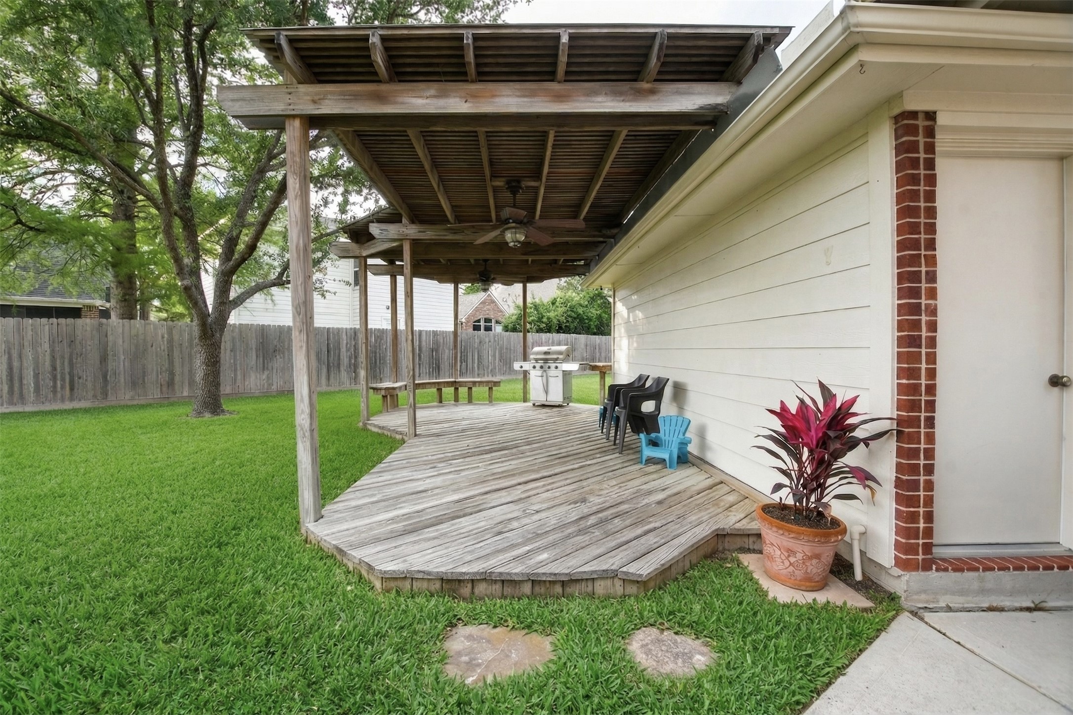 20423 Forest Drive Spring, TX 77388 - Photo 40 of 49 This photo showcases a spacious backyard with a wooden deck and pergola, perfect for outdoor relaxation. The area is complemented by a barbecue grill and seating, surrounded by a well-maintained lawn and a privacy fence.