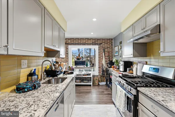 a kitchen with granite countertop a stove a sink a refrigerator and cabinets