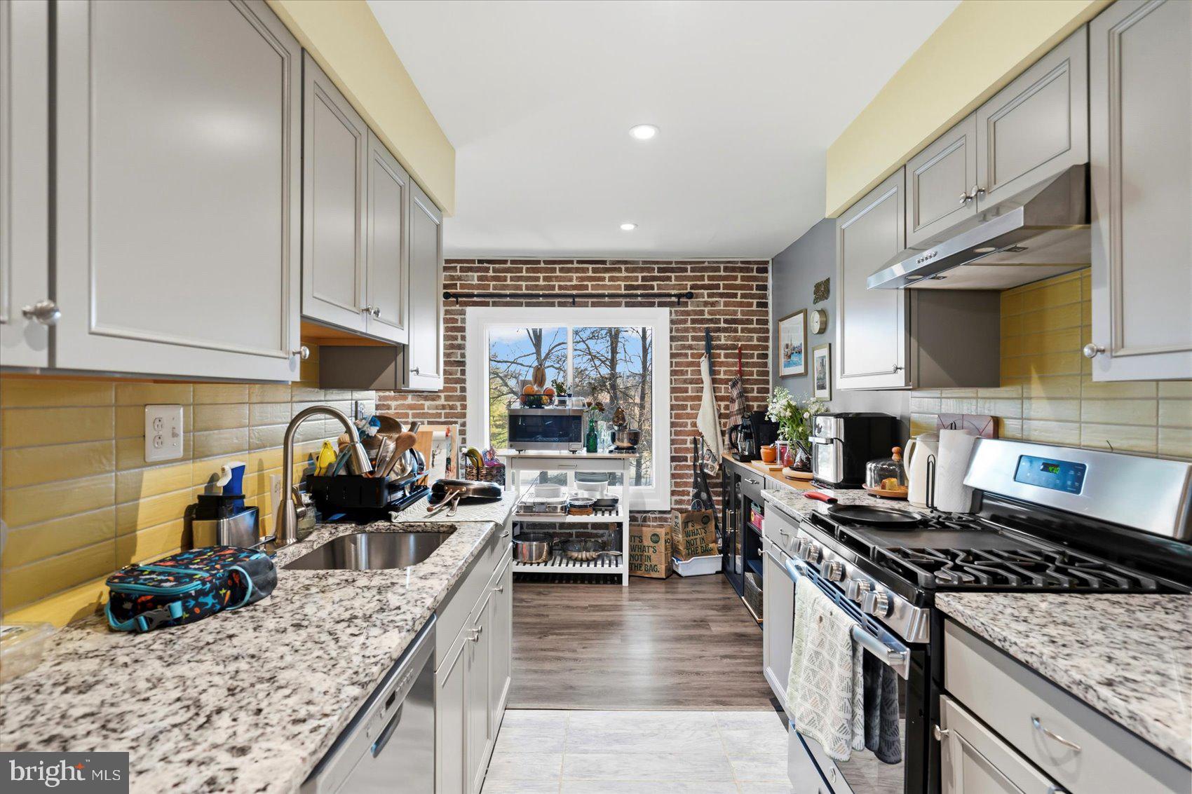 5239 West Running Brook Road, Unit 302 Columbia, MD 21044 - Photo 7 of 33 a kitchen with granite countertop a stove a sink a refrigerator and cabinets