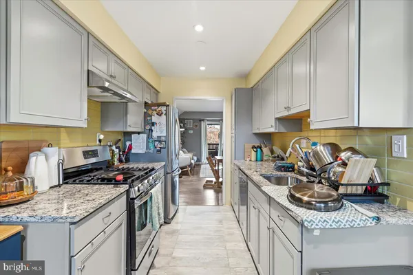 a kitchen with stainless steel appliances granite countertop a stove top oven a sink a counter space and cabinets