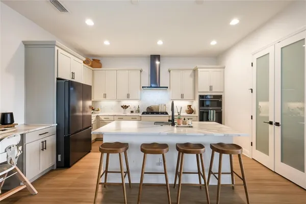 a kitchen with granite countertop a refrigerator stove microwave and cabinets with wooden floor