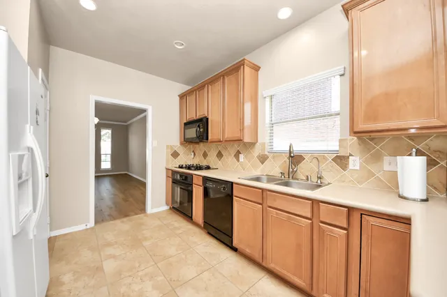 a kitchen with stainless steel appliances granite countertop a sink dishwasher stove and refrigerator