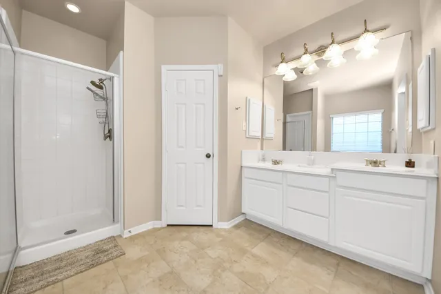 a bathroom with a double vanity sink mirror and shower