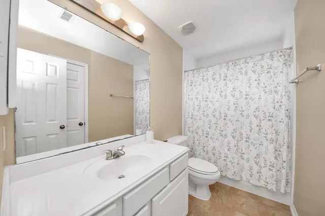 a bathroom with a sink a toilet and shower curtain