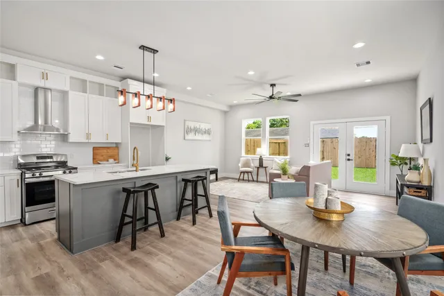 a kitchen with a stove a kitchen island a dining table and chairs with wooden floor