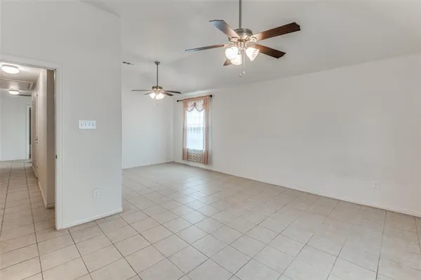 an empty room with chandelier fan and windows