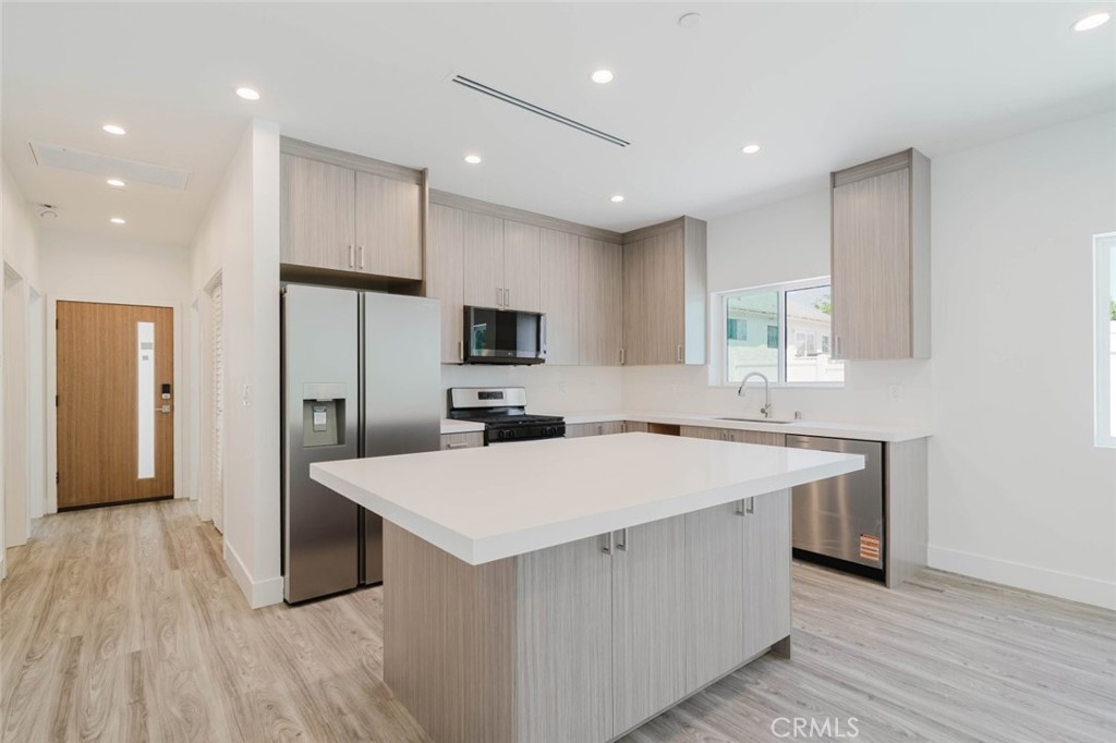 17846 Rinaldi Street Granada Hills, CA 91344 - Photo 13 of 34 a large kitchen with kitchen island a sink dishwasher a refrigerator and a stove with wooden floor