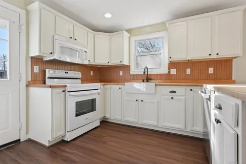 a kitchen with granite countertop white cabinets and white appliances