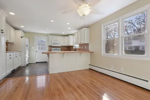 a kitchen with stainless steel appliances granite countertop a stove top oven a sink dishwasher and a refrigerator with wooden floor