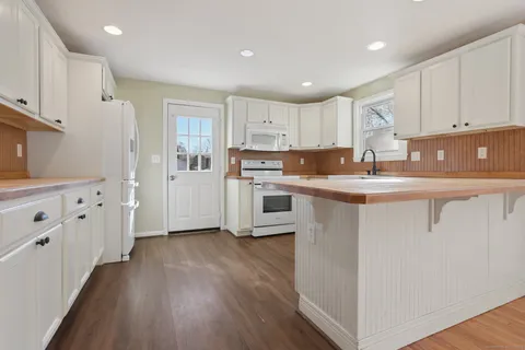 a kitchen with kitchen island a sink a stove a refrigerator and white cabinets