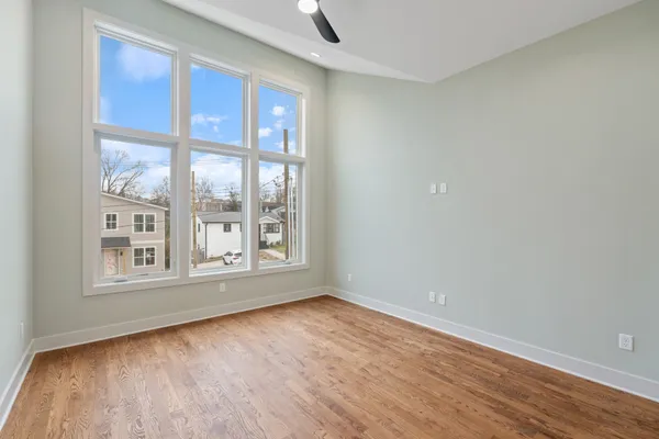 an empty room with wooden floor and windows