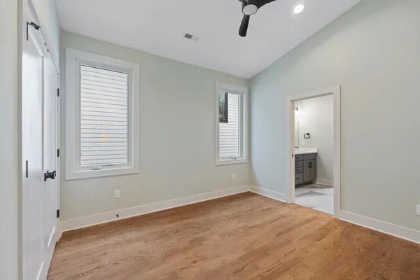 a view of an empty room with a window and chandelier fan