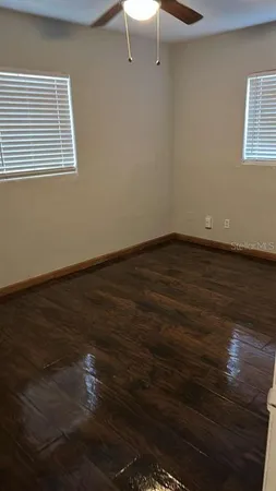 a view of an empty room with wooden floor and a window