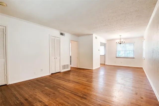 a view of an empty room with a window and wooden floor