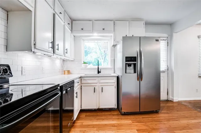 a kitchen with stainless steel appliances a sink cabinets and wooden floor