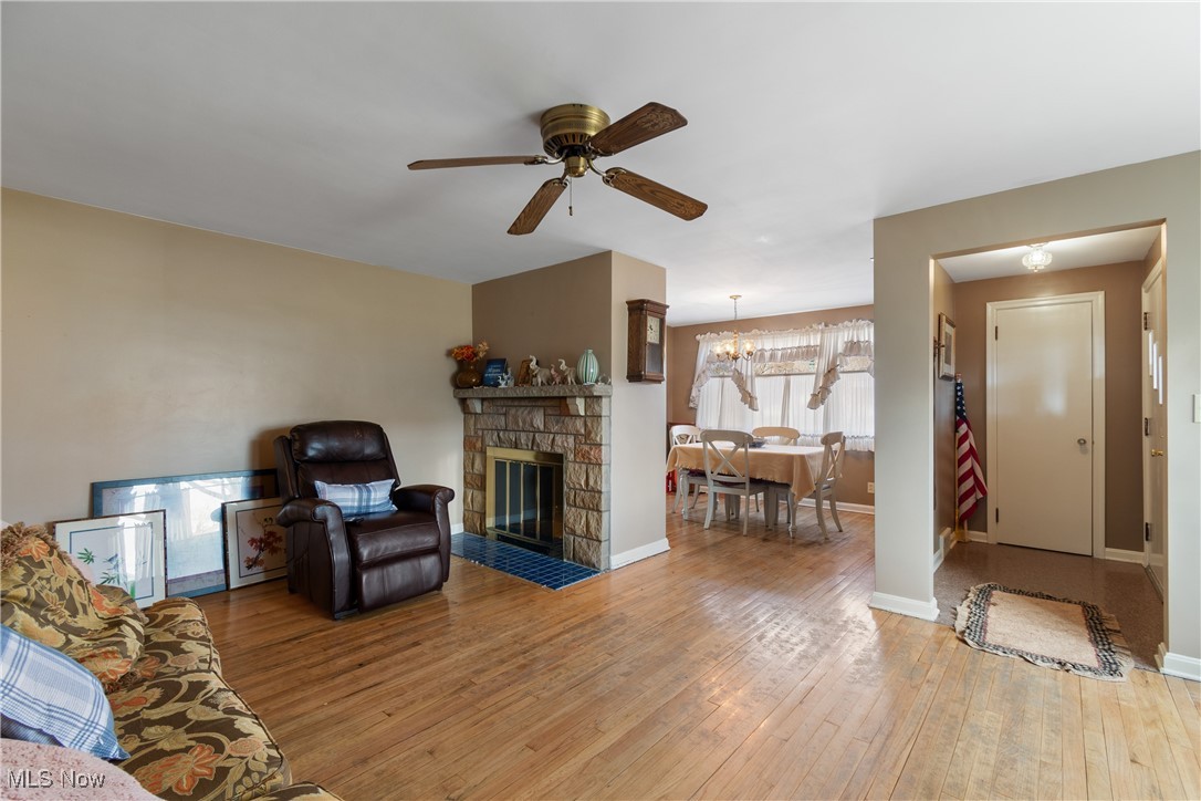 1527 Ridge Road Northwest Canton, OH 44703 - Photo 5 of 27 Living room with ceiling fan with notable chandelier, a stone fireplace, and hardwood / wood-style floors