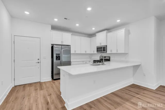 a large white kitchen with wooden floor and a sink