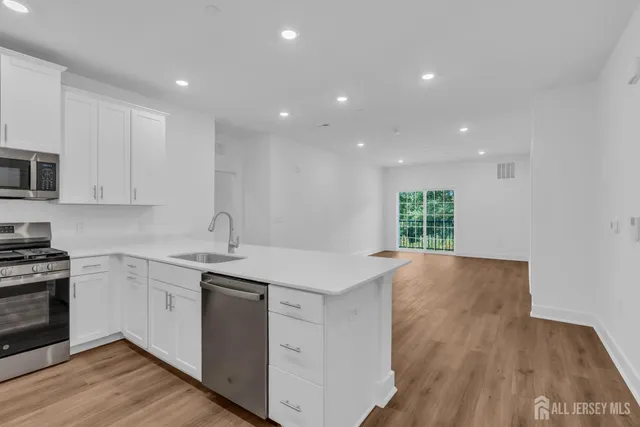 a kitchen with granite countertop white cabinets and stainless steel appliances