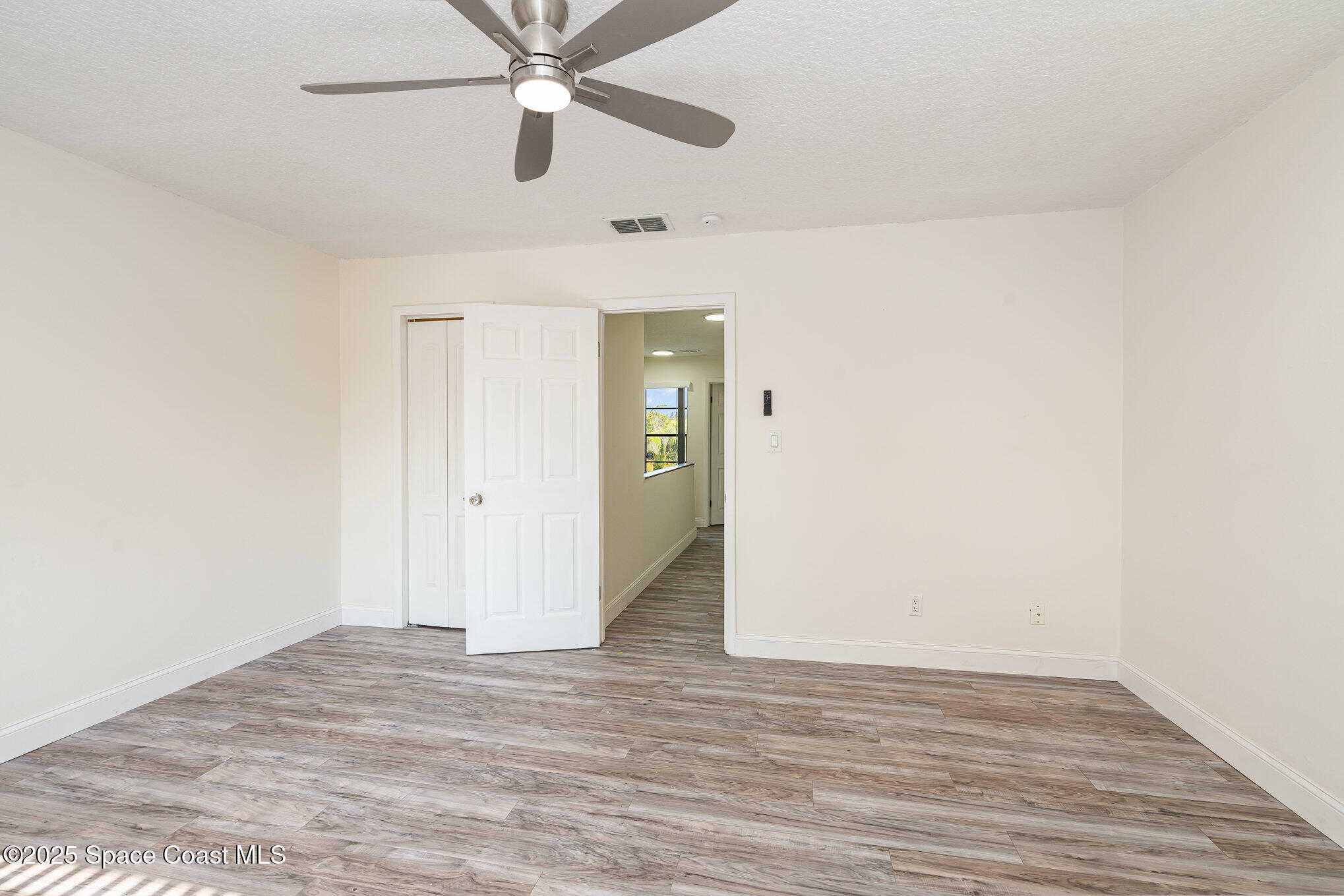 3444 Partridge Court Melbourne, FL 32935 - Photo 19 of 78 an empty room with wooden floor ceiling fan and windows