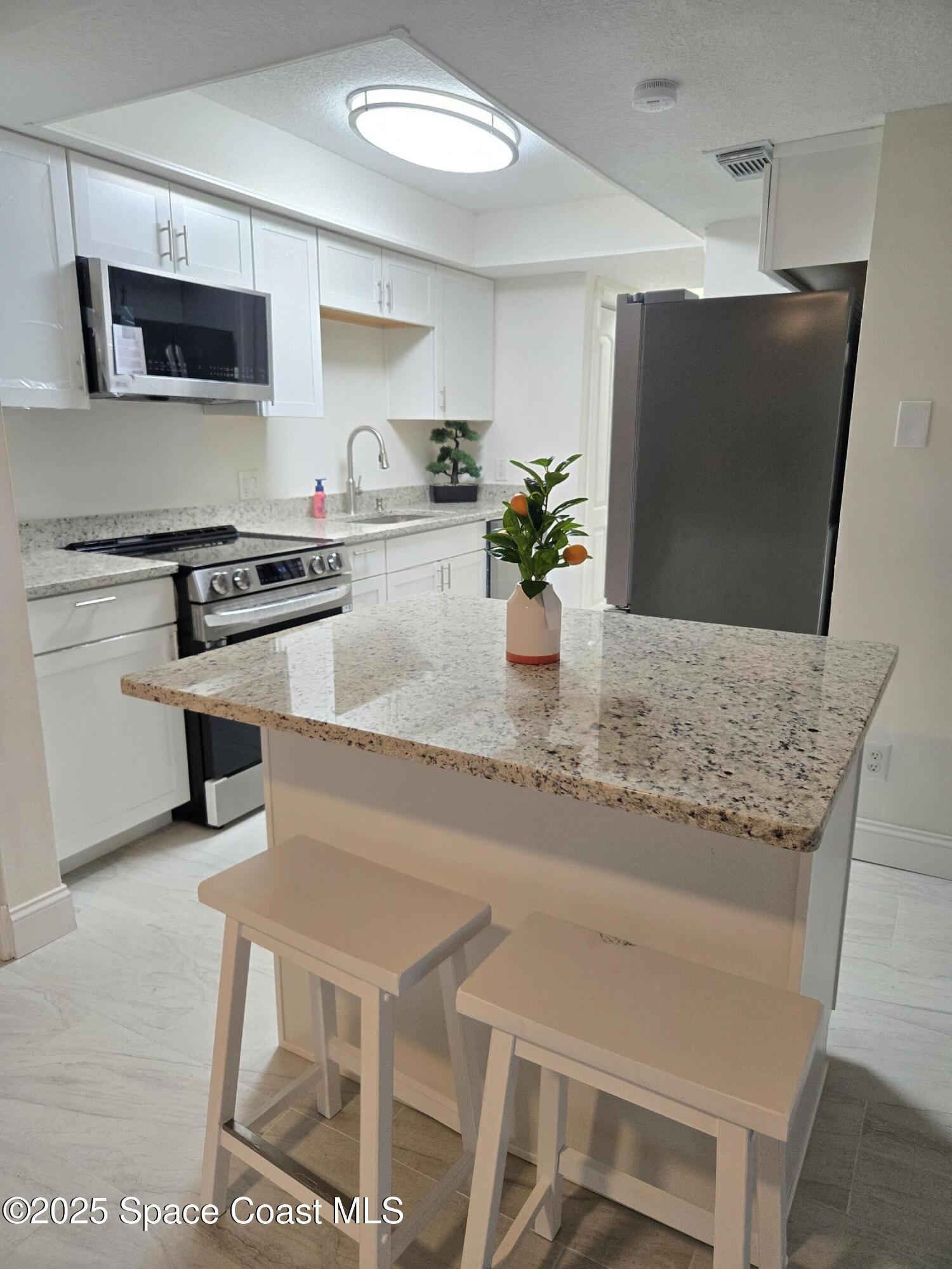 3444 Partridge Court Melbourne, FL 32935 - Photo 52 of 78 a kitchen with stainless steel appliances granite countertop a stove a sink and a microwave