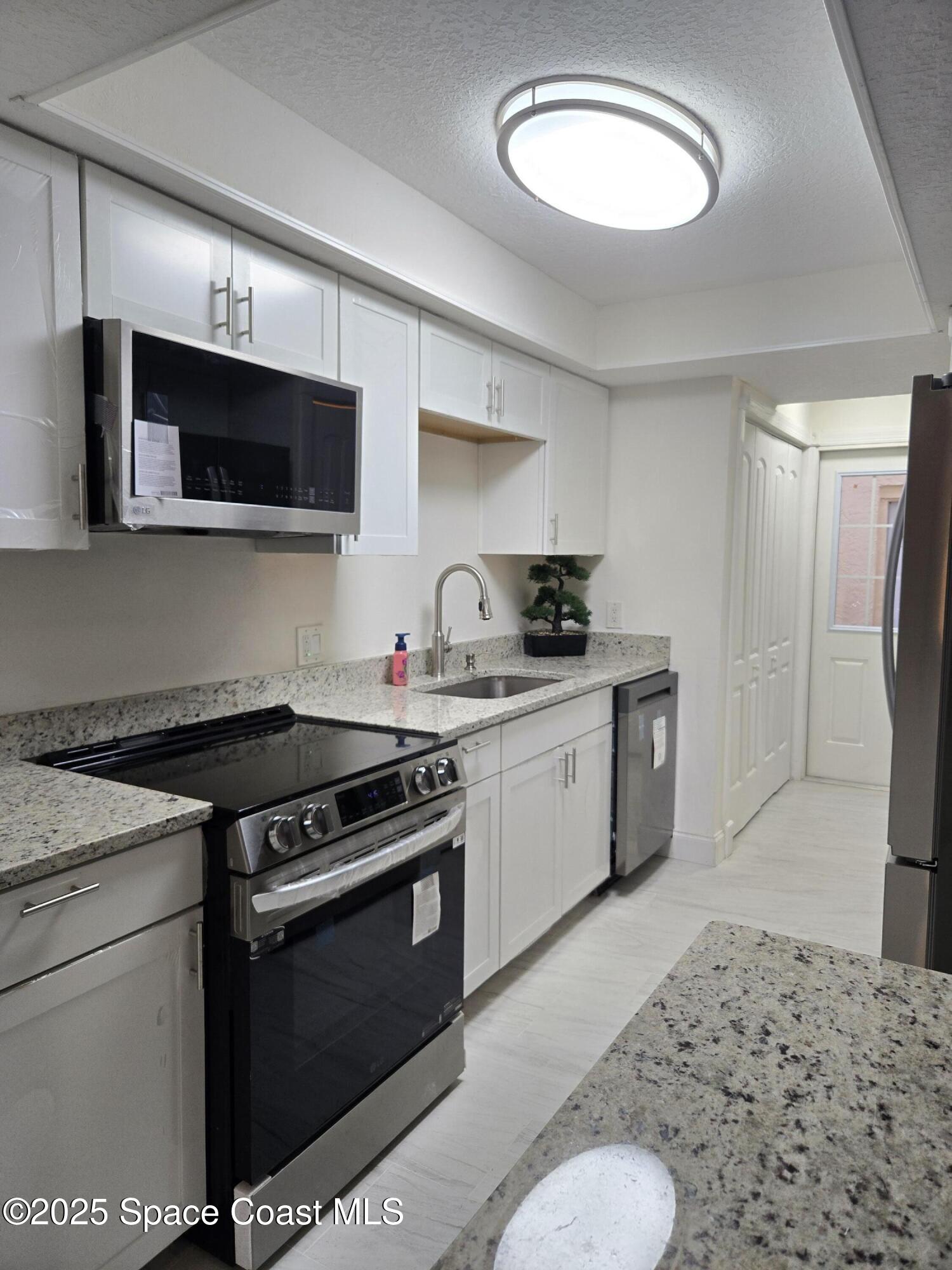 3444 Partridge Court Melbourne, FL 32935 - Photo 53 of 78 a kitchen with stainless steel appliances granite countertop a stove a sink and a microwave