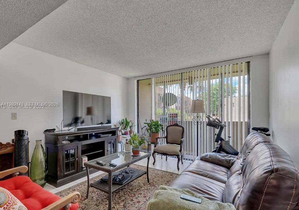 8002 Southwest 149th Avenue, Unit B201 Miami, FL 33193 - Photo 9 of 13 a living room with furniture a flat screen tv and a fireplace