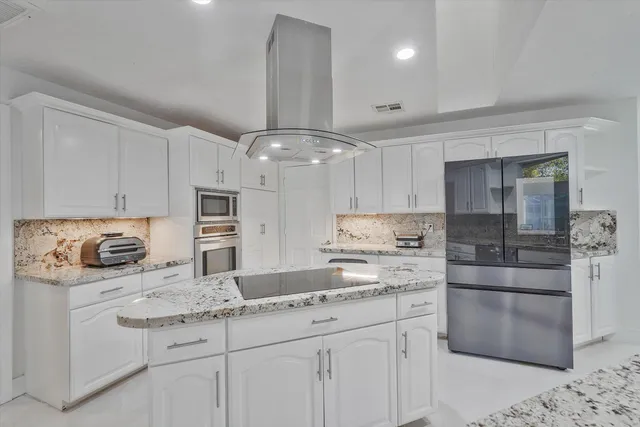 a kitchen with kitchen island granite countertop a sink cabinets and stainless steel appliances