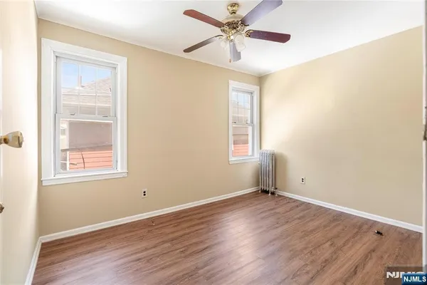 an empty room with wooden floor fan and windows