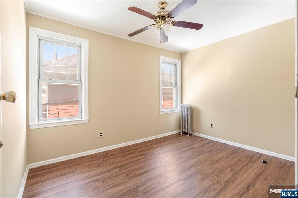 24 Swaine Place, Unit 22 West Orange, NJ 07052 - Photo 26 of 27 an empty room with wooden floor fan and windows