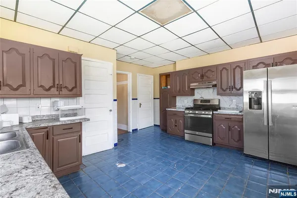 a kitchen with stainless steel appliances granite countertop a refrigerator a sink dishwasher a stove with wooden cabinets