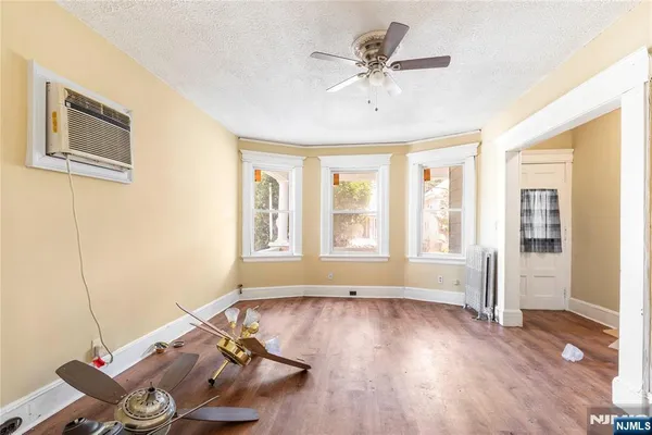 a view of an empty room with a window and wooden floor