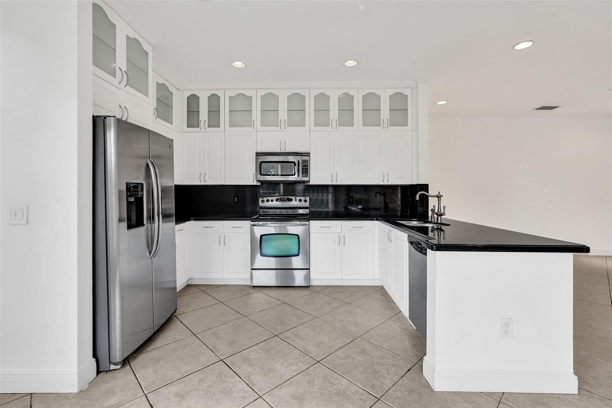 10902 Tamoron Lane Boca Raton, FL 33498 - Photo 16 of 66 a kitchen with stainless steel appliances kitchen island granite countertop a refrigerator and a stove top oven