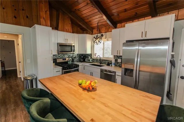 a kitchen with stainless steel appliances kitchen island granite countertop a refrigerator a stove a sink a dining table and chairs with wooden floor