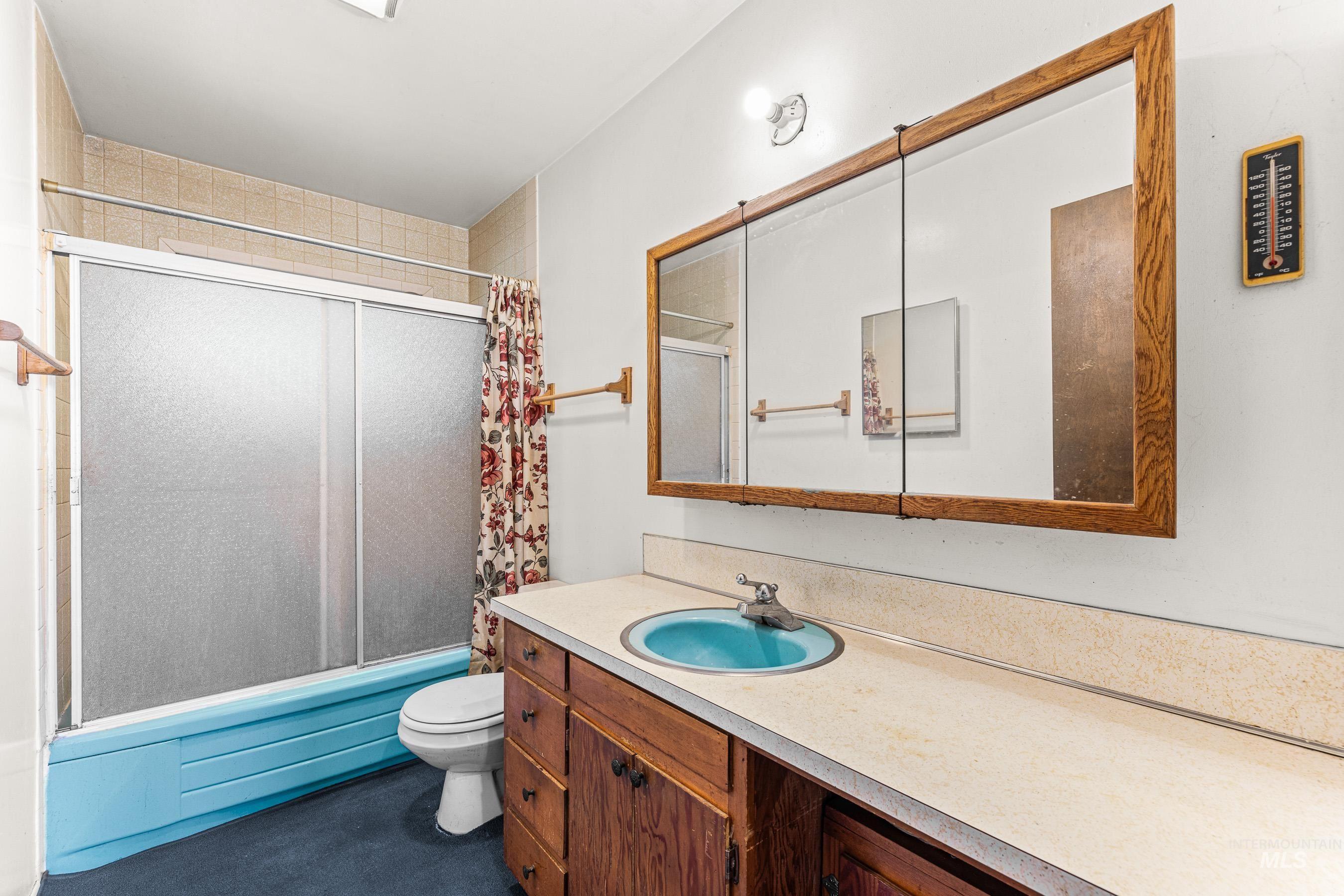7026 S Highway Riggins, ID 83549 - Photo 33 of 50 Bathroom featuring a vanity with a blue basin and wood-finish cabinetry, a framed medicine cabinet, and a tiled shower with sliding glass doors