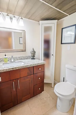 a bathroom with a granite countertop toilet sink and mirror