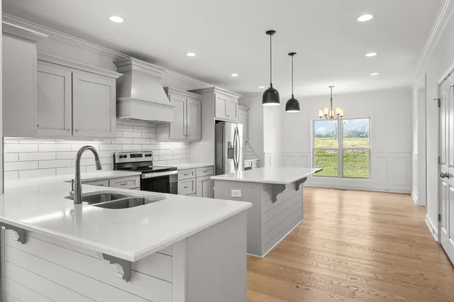 a kitchen with stainless steel appliances a sink a stove a refrigerator and cabinets