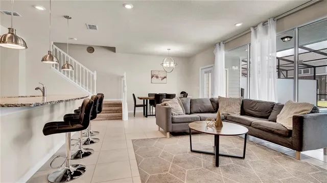 a kitchen with stainless steel appliances kitchen island granite countertop a stove a sink a refrigerator a dining table and chairs