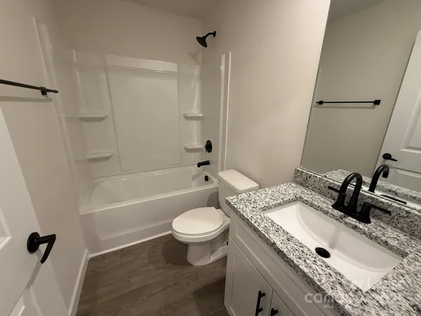 a bathroom with a granite countertop sink toilet a mirror and shower