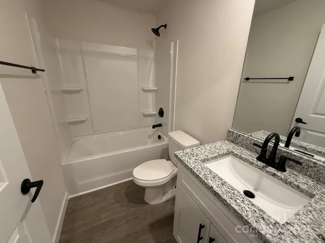 a bathroom with a granite countertop sink toilet a mirror and shower