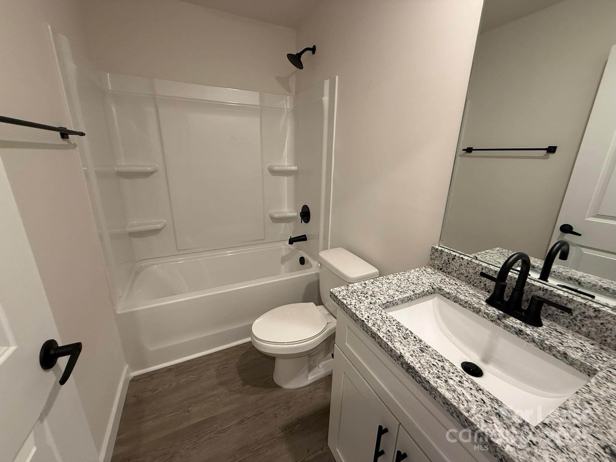 144 33rd Street Northwest, Unit B Hickory, NC 28601 - Photo 11 of 14 a bathroom with a granite countertop sink toilet a mirror and shower